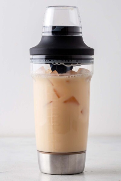 Vanilla syrup, tea, ice, and milk in a cocktail shaker. 