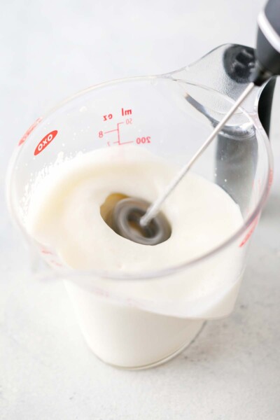 Frothing milk in a measuring cup.