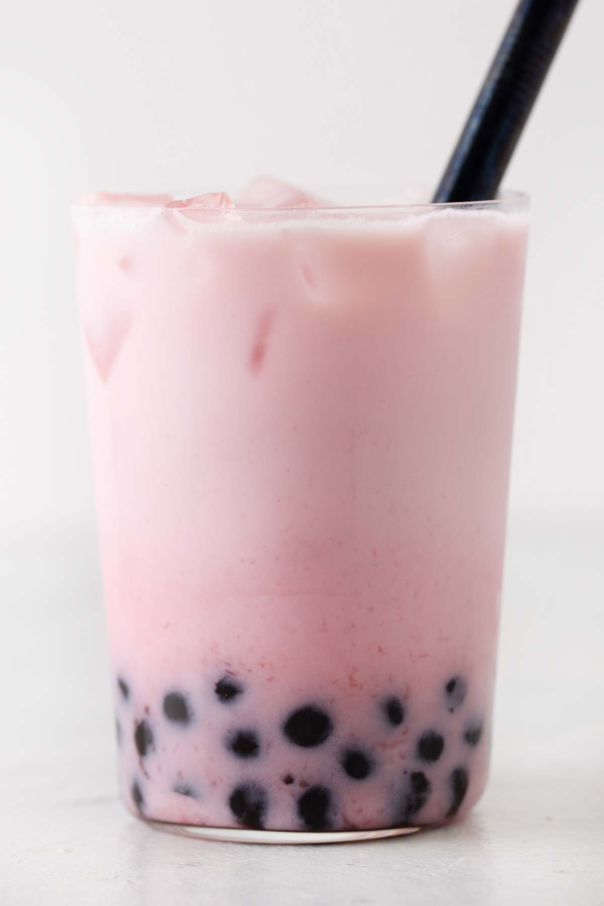 Strawberry milk tea with boba in a glass cup.