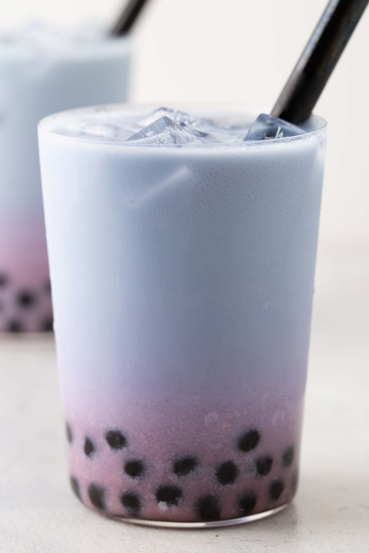 Strawberry and Butterfly Pea Flower Latte Bubble Tea with the layers combined to an ombre look with a wide straw.