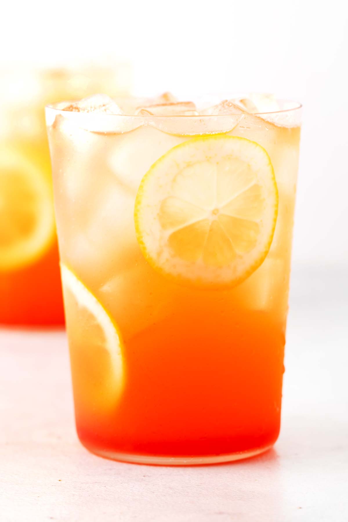 Strawberry Green Tea Lemonade in clear glass with sliced lemons.