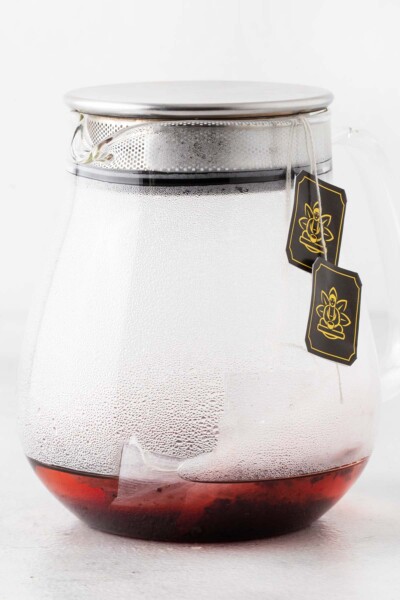 Hibiscus tea bags being steeped in teapot with lid.