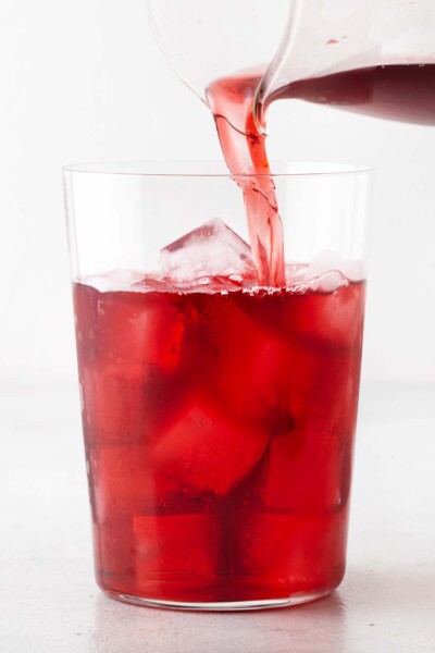 Hibiscus tea being poured into cup holding ice.
