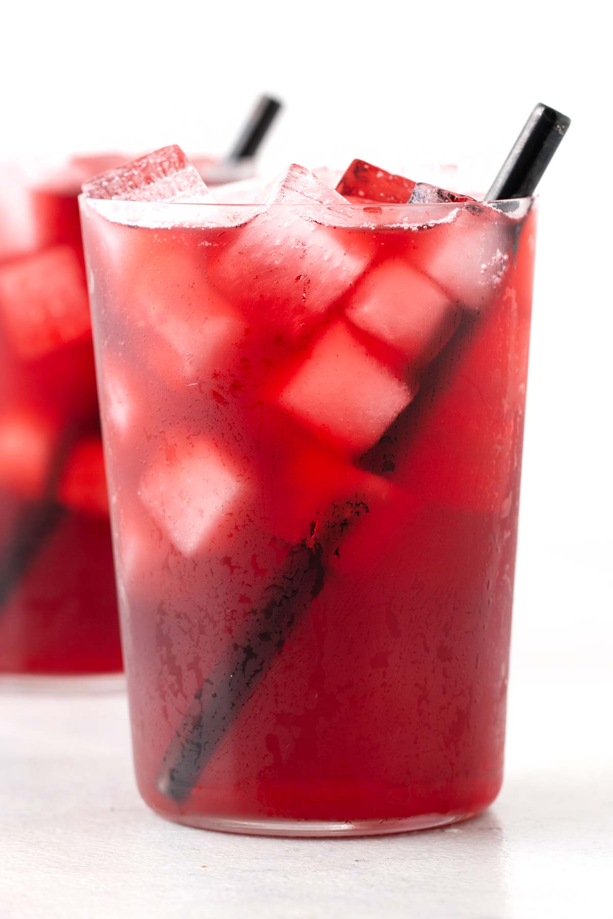Strawberry Hibiscus Iced Tea in clear cup with straw.