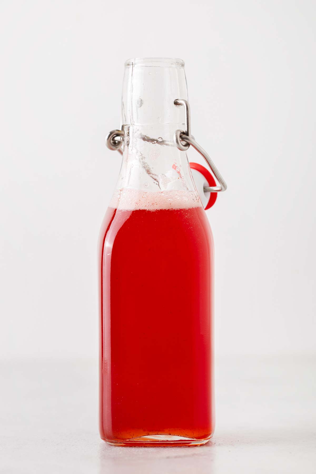 Homemade strawberry syrup in a glass bottle.