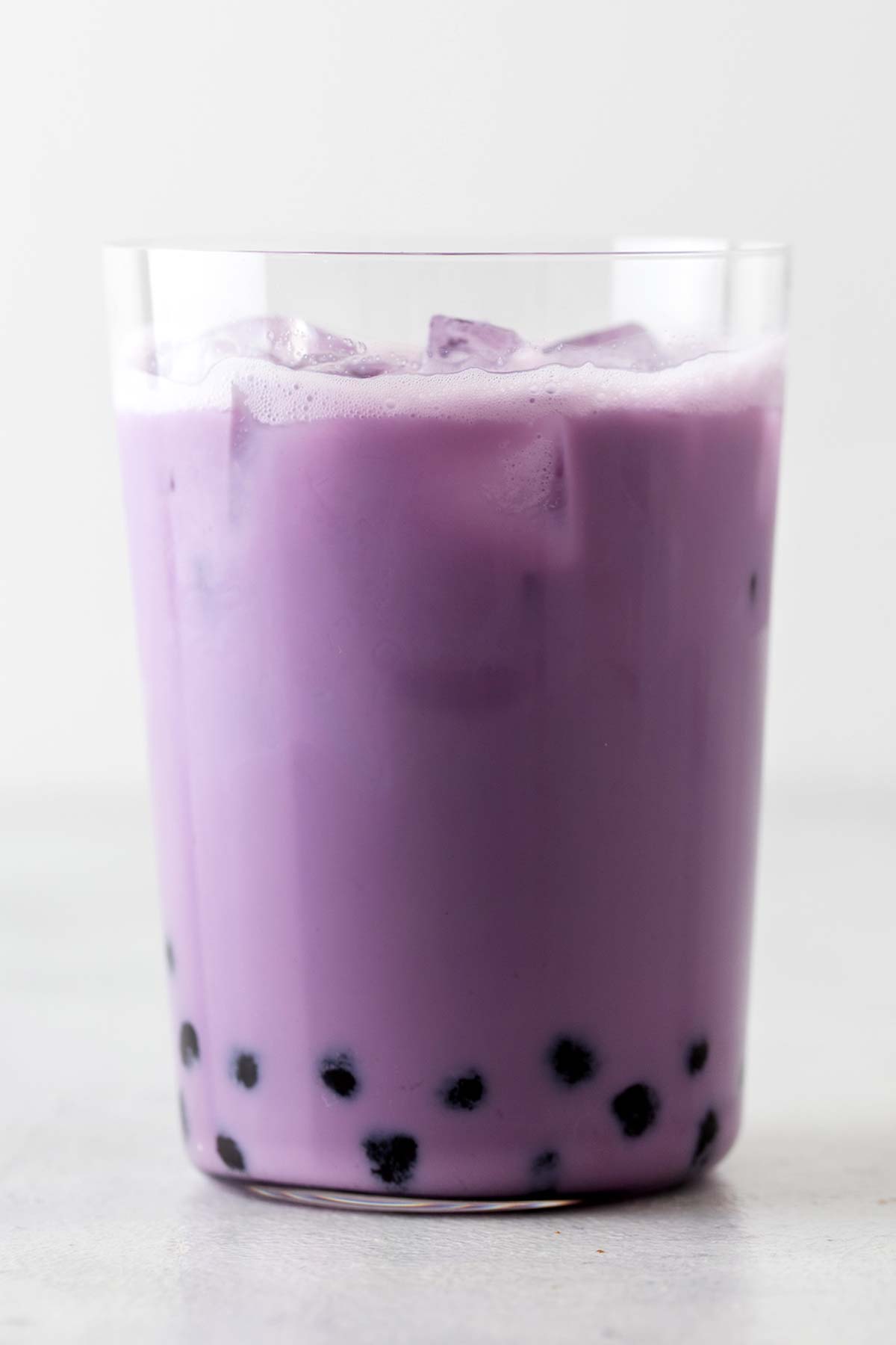 Easy Taro Milk Bubble Tea, purple drink with black tapioca balls in a clear glass with ice.